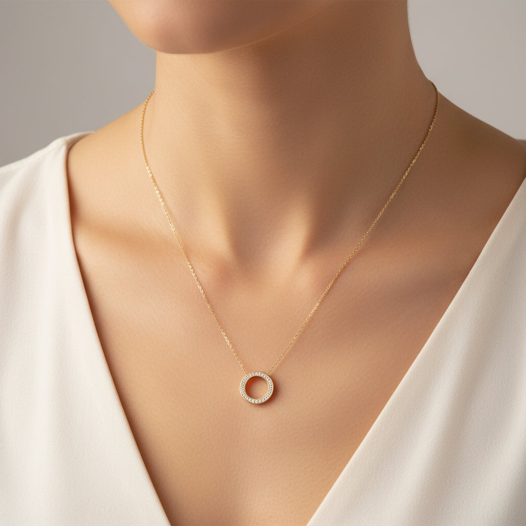 Gold necklace with a circular pendant on a white background