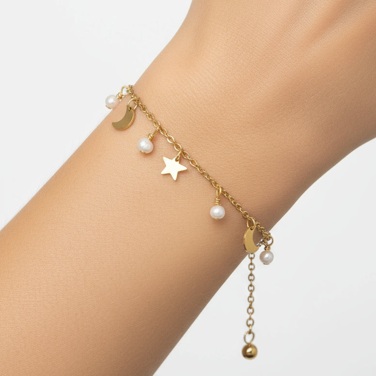 Gold bracelet with star, moon, and heart charms on a white background