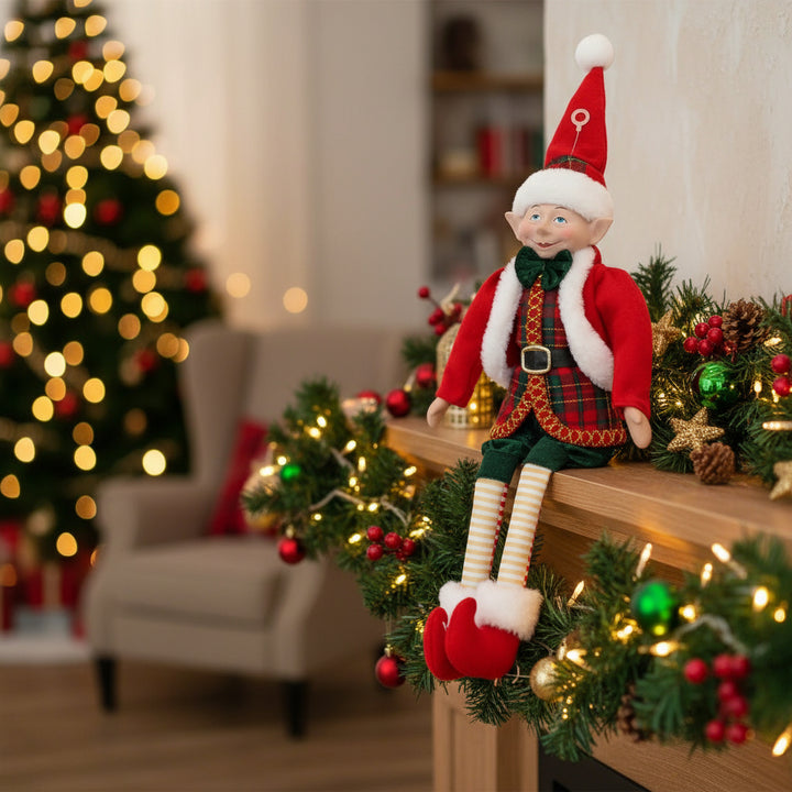 Christmas elf doll in red and green outfit with Santa hat on a white background