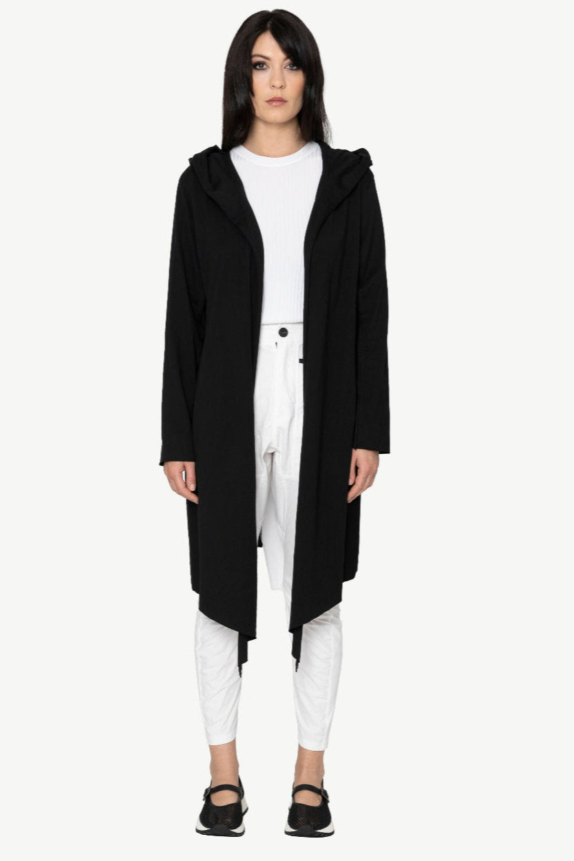 Person wearing a long black coat over a white outfit on a white background