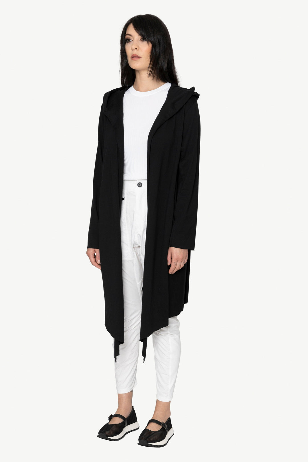 Person wearing a black coat over a white outfit on a white background