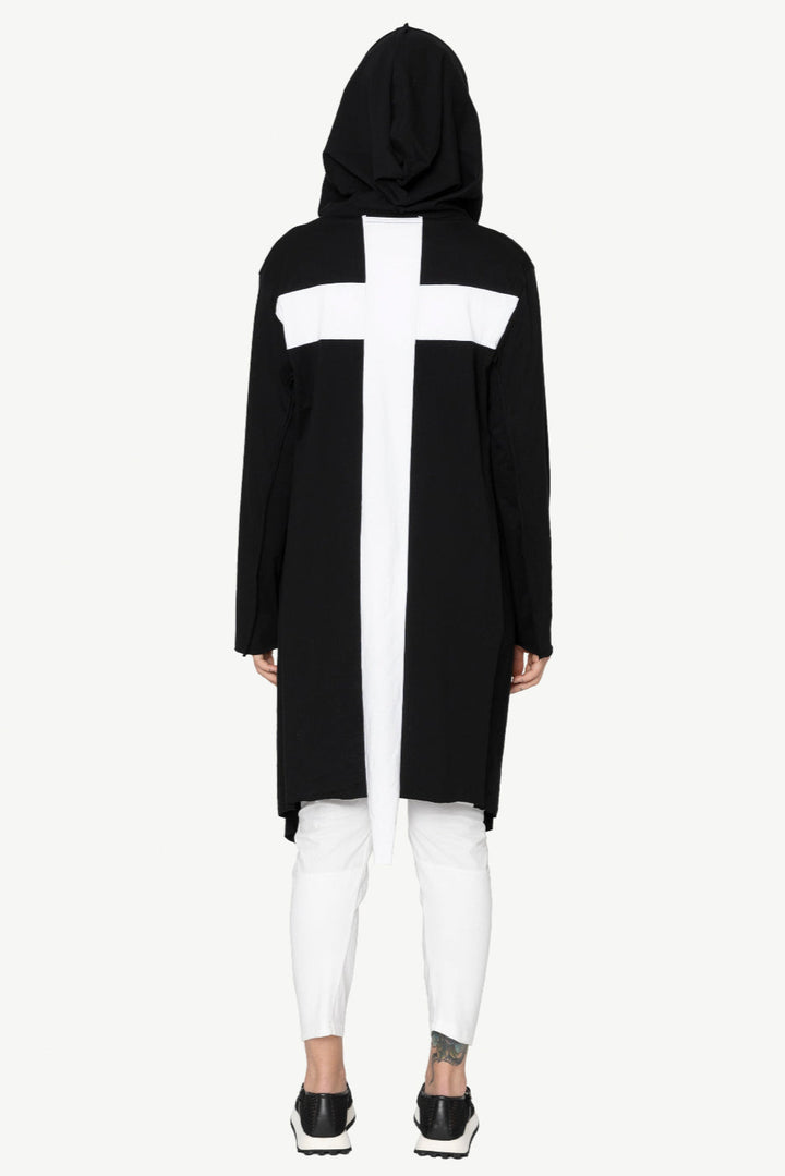 Person wearing a black hoodie with a white cross design on a white background