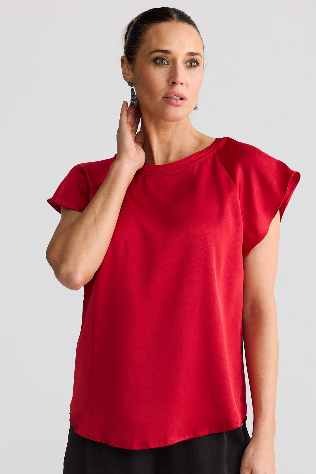 Woman wearing a red top and black shorts on a plain background