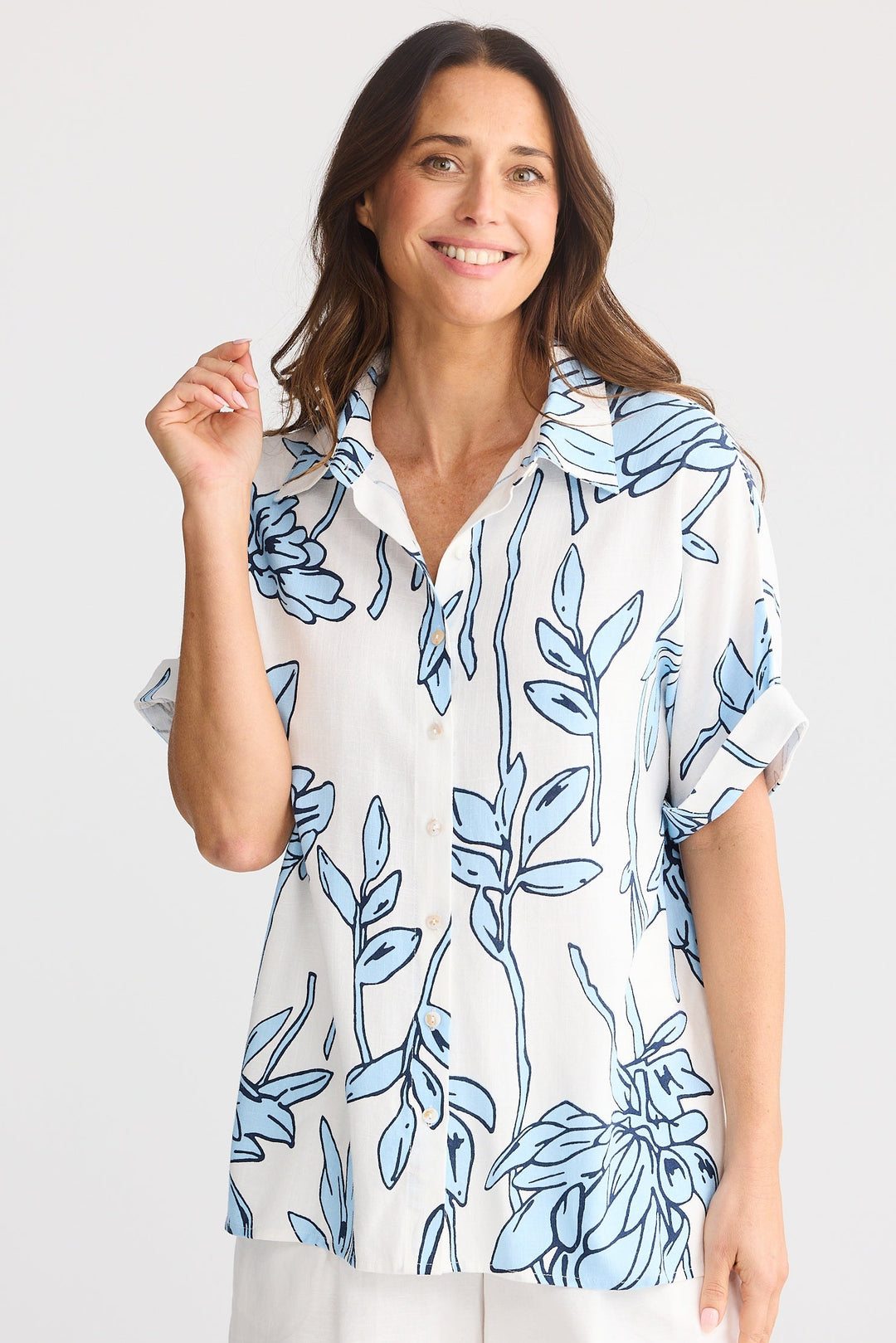 Woman wearing a white blouse with blue floral pattern and white shorts on a white background