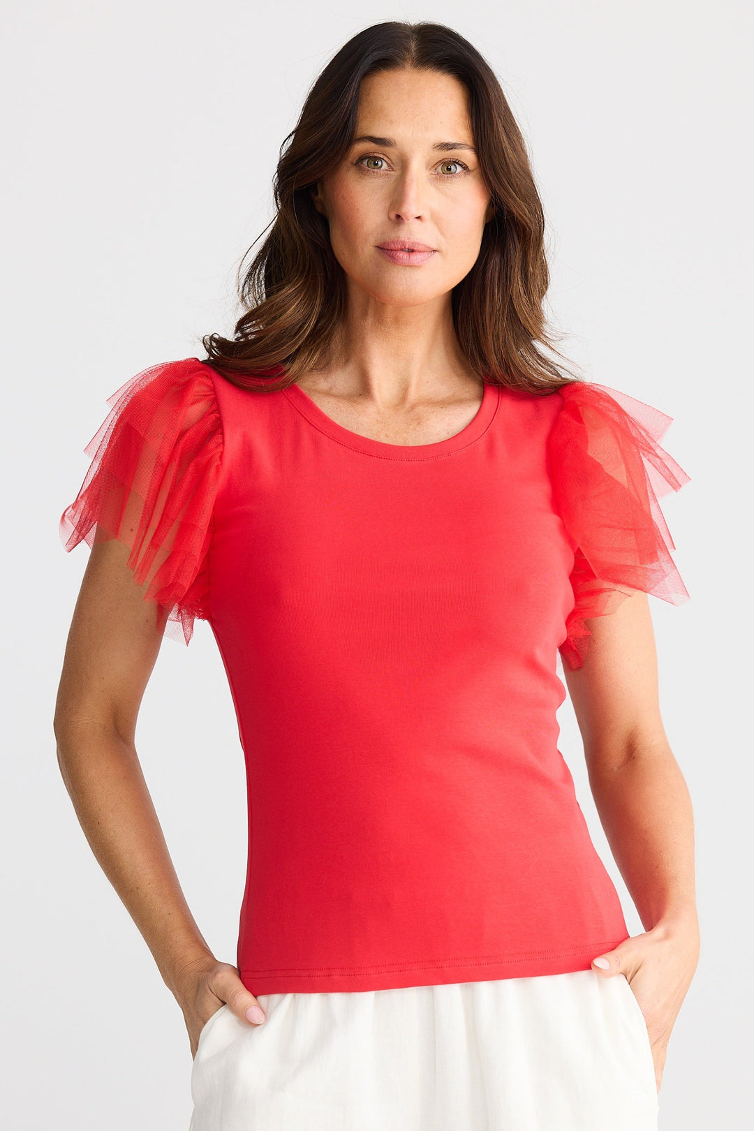 Woman wearing a red top with tulle sleeves on a white background