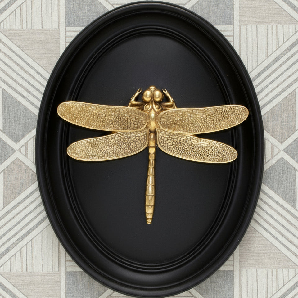 Gold dragonfly sculpture in a black oval frame