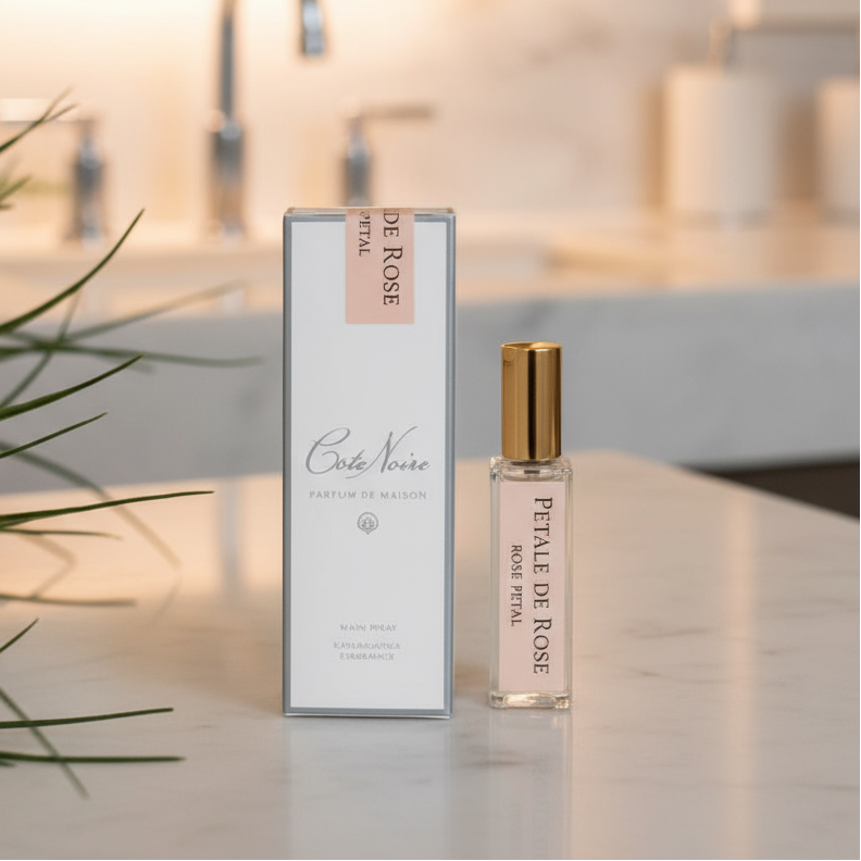 A fragrance refill bottle with a pink label, next to its packaging box which also has pink accents. The background is white with some plant foliage on the left side.