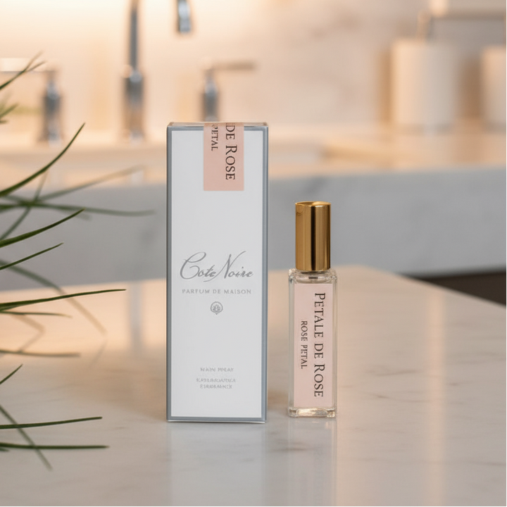 A fragrance refill bottle with a pink label, next to its packaging box which also has pink accents. The background is white with some plant foliage on the left side.