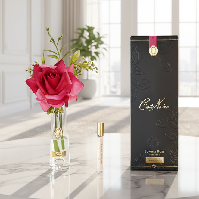 Vase with pink rose and Cote Noire perfume bottle on a white background