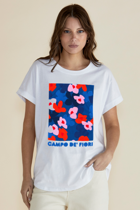 Woman wearing a white t-shirt with a colorful floral design and 'Campo de Fiori' text on a beige background