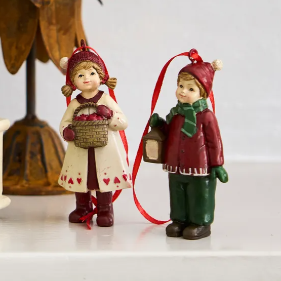 Two Christmas-themed figurines on a white surface with a decorative background.