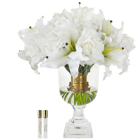 Clear glass vase with white flowers and a small bottle on a white background