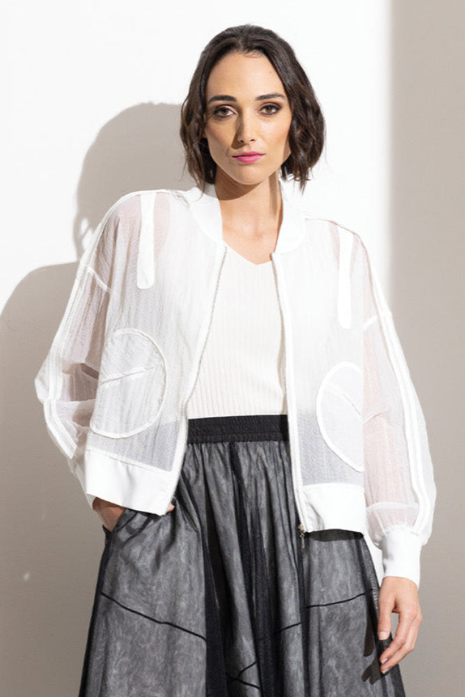 Woman wearing a white blouse, black skirt, and sandals against a plain background