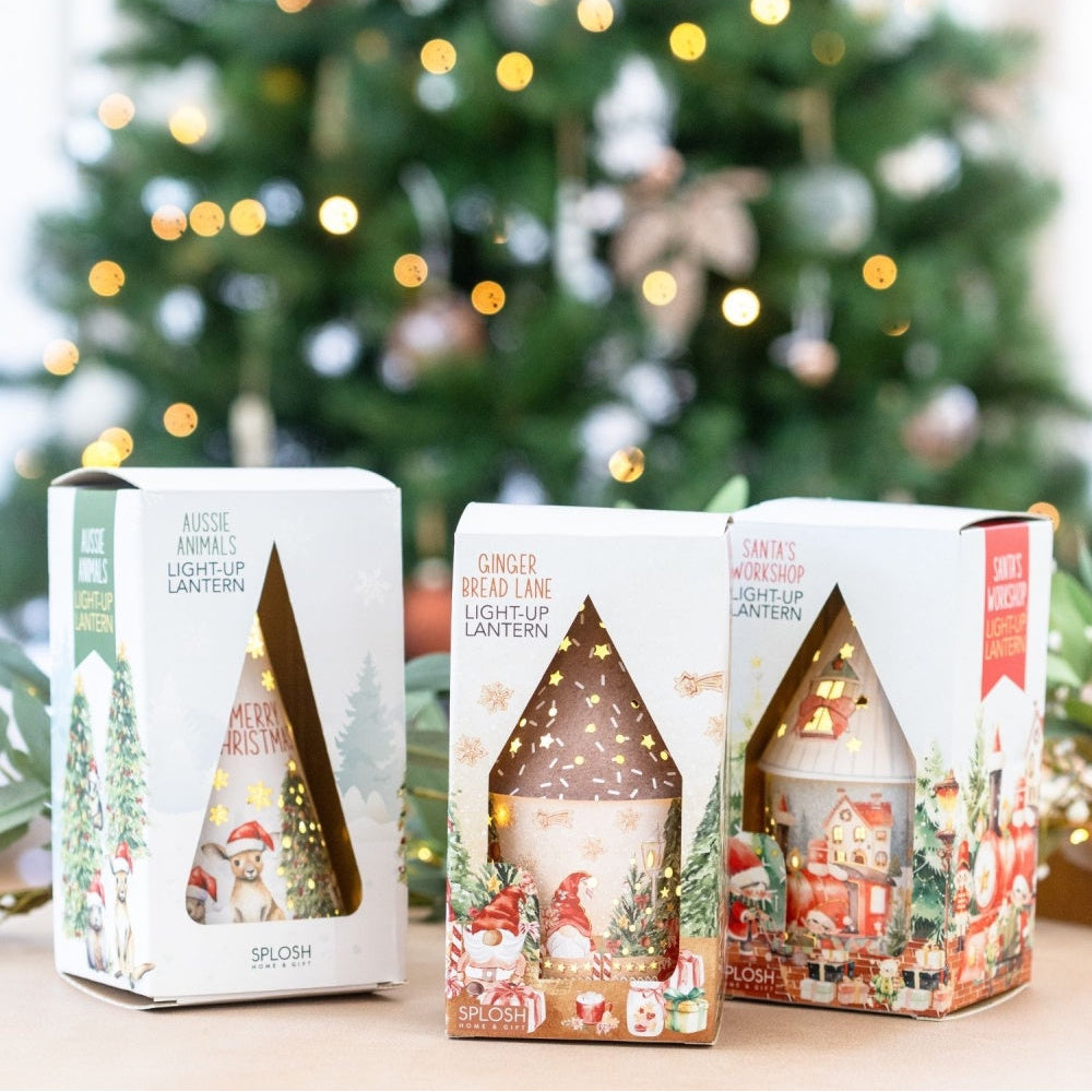 Three Christmas-themed light-up lanterns in packaging with a festive background.
