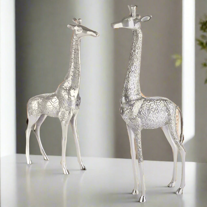 Two silver giraffe figurines on a white background