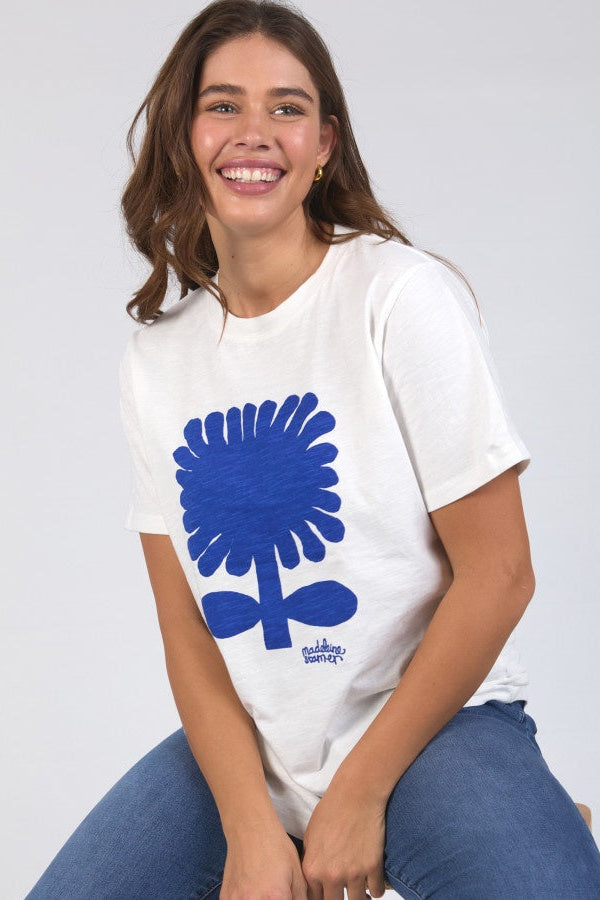 Person wearing a white t-shirt with a blue floral design on a plain background
