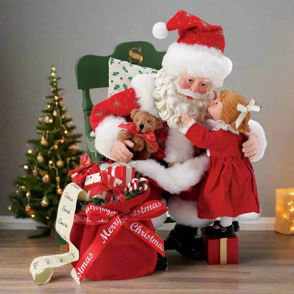 Decorative figurine of Santa Claus with a child and teddy bear on a white background