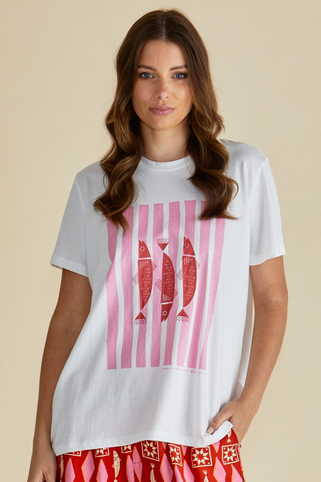 Woman wearing a white betty basics t-shirt with pink graphic design on a beige background