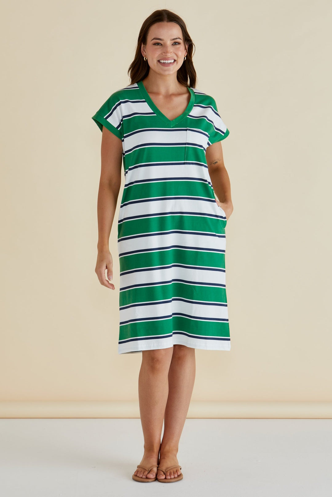 Woman wearing a green and white striped BETTY BASICS dress against a beige background