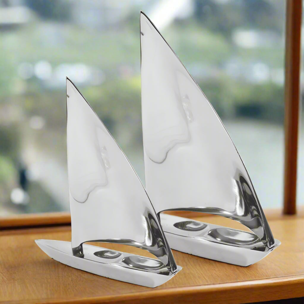 Two silver sailboat models on a white background