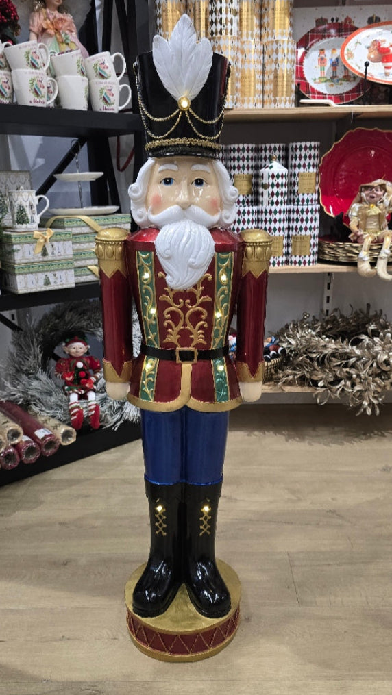 Decorative nutcracker figure in a store setting with Christmas decorations.