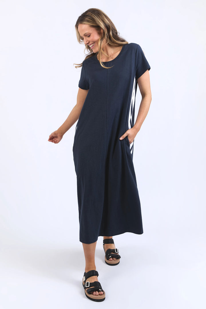 Woman wearing a navy blue dress with white stripes on a white background