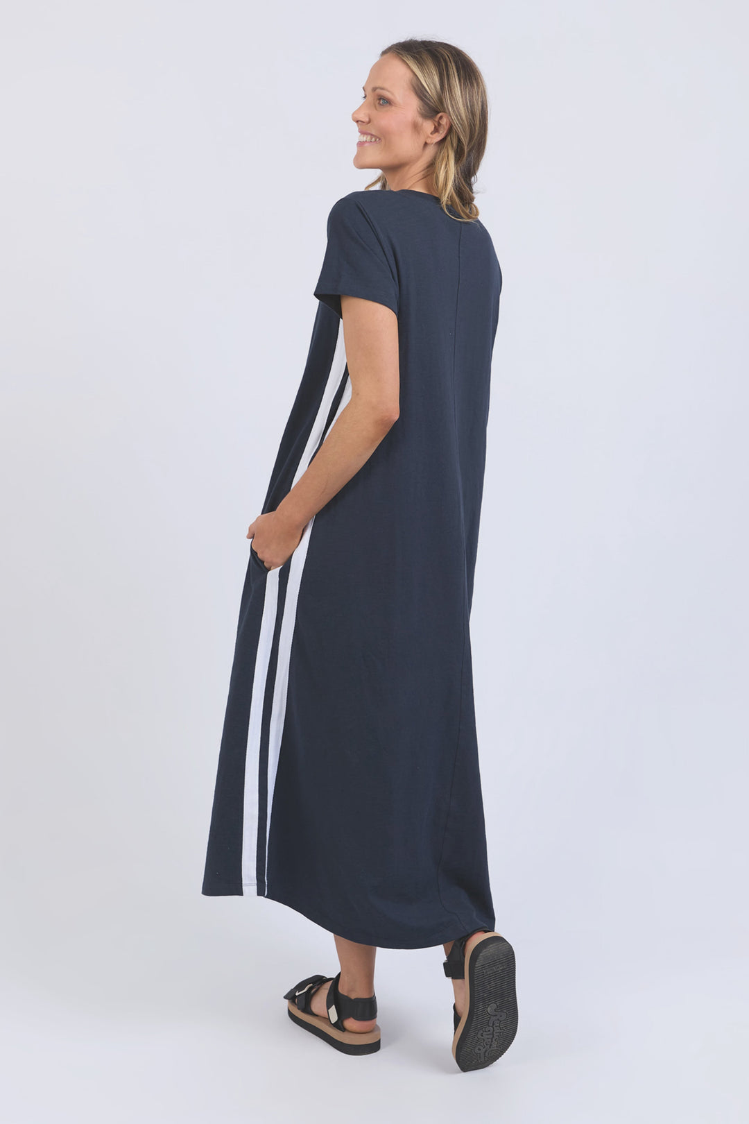 Woman wearing a navy dress with white stripes on a white background