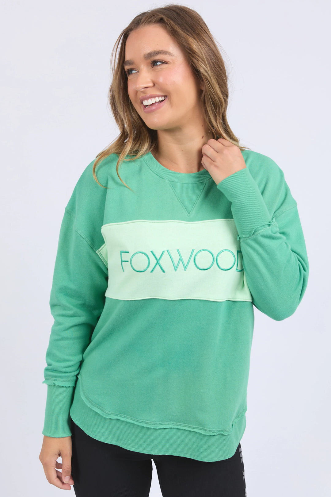 Woman wearing a green sweatshirt with 'FOXWOOD' logo on a white background