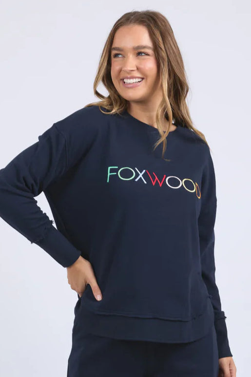 Woman wearing a navy sweatshirt with 'FOXWOOD' logo on a white background