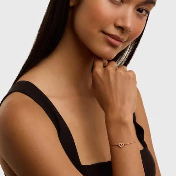 Woman wearing a heart-shaped bracelet on a plain background
