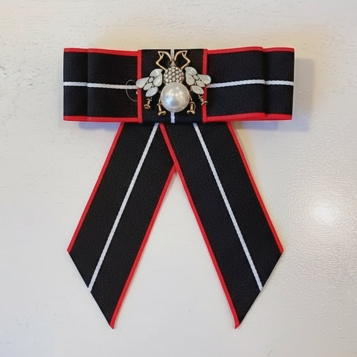 Decorative bow with black, red, and white ribbons in a decorative box.