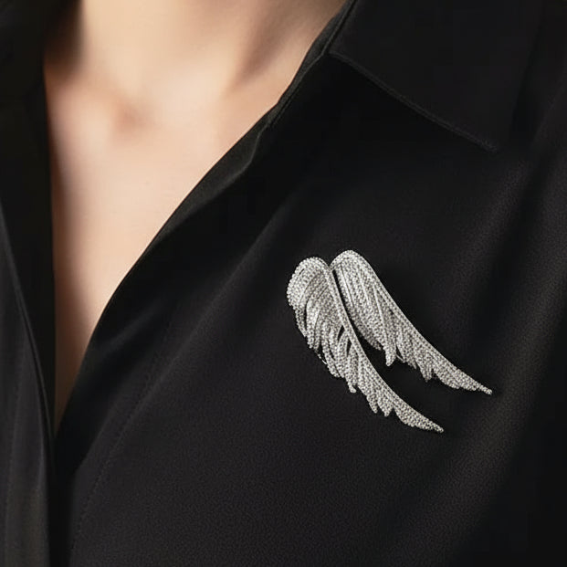 Silver angel wing brooch on a black background