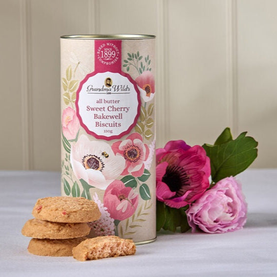 Biscuit tin with floral design and cookies on a light surface