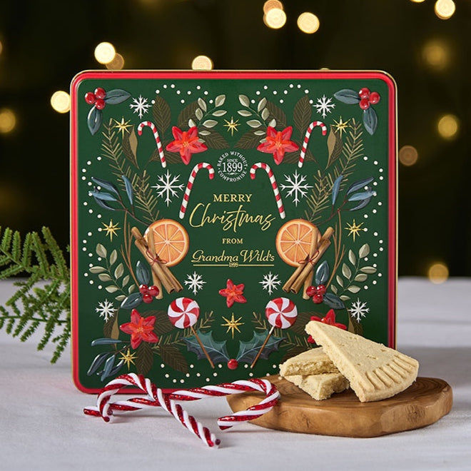 Decorative Christmas cookie tin with cookies on a wooden board against a festive background.