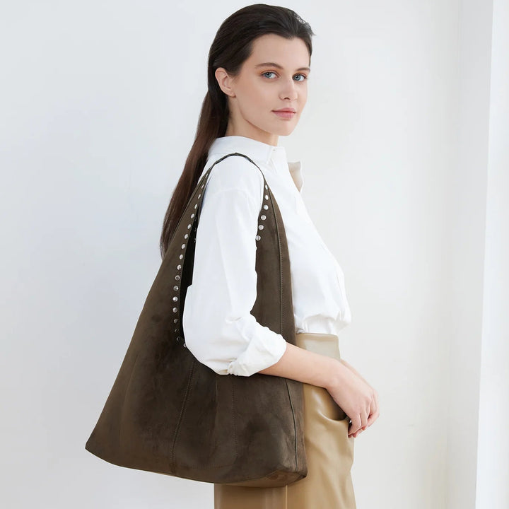 Woman wearing a brown leather bag over her shoulder against a white background