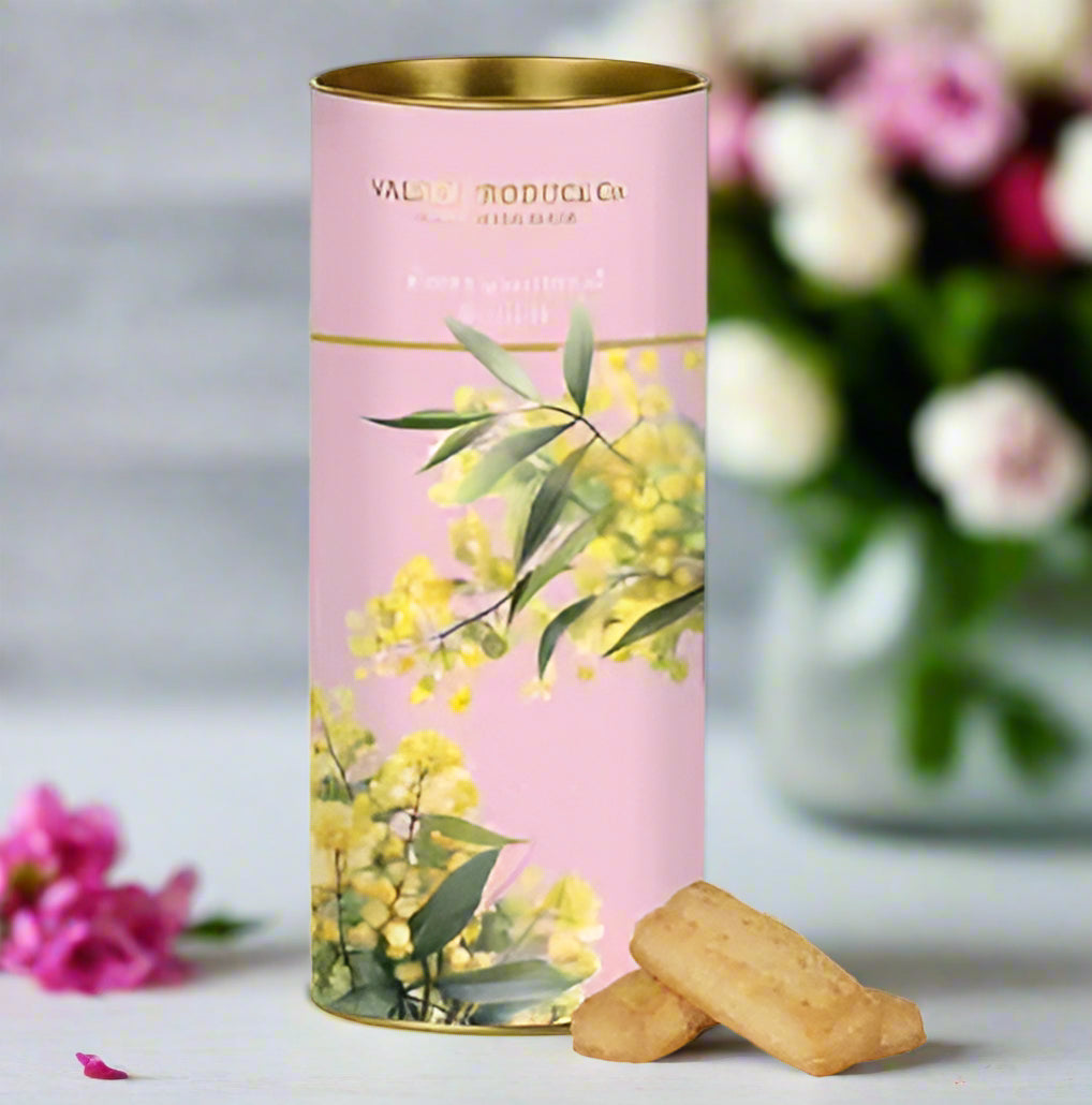 Decorative cylindrical cookie tin with floral design and a small SHORTBREAD cookie on a white background