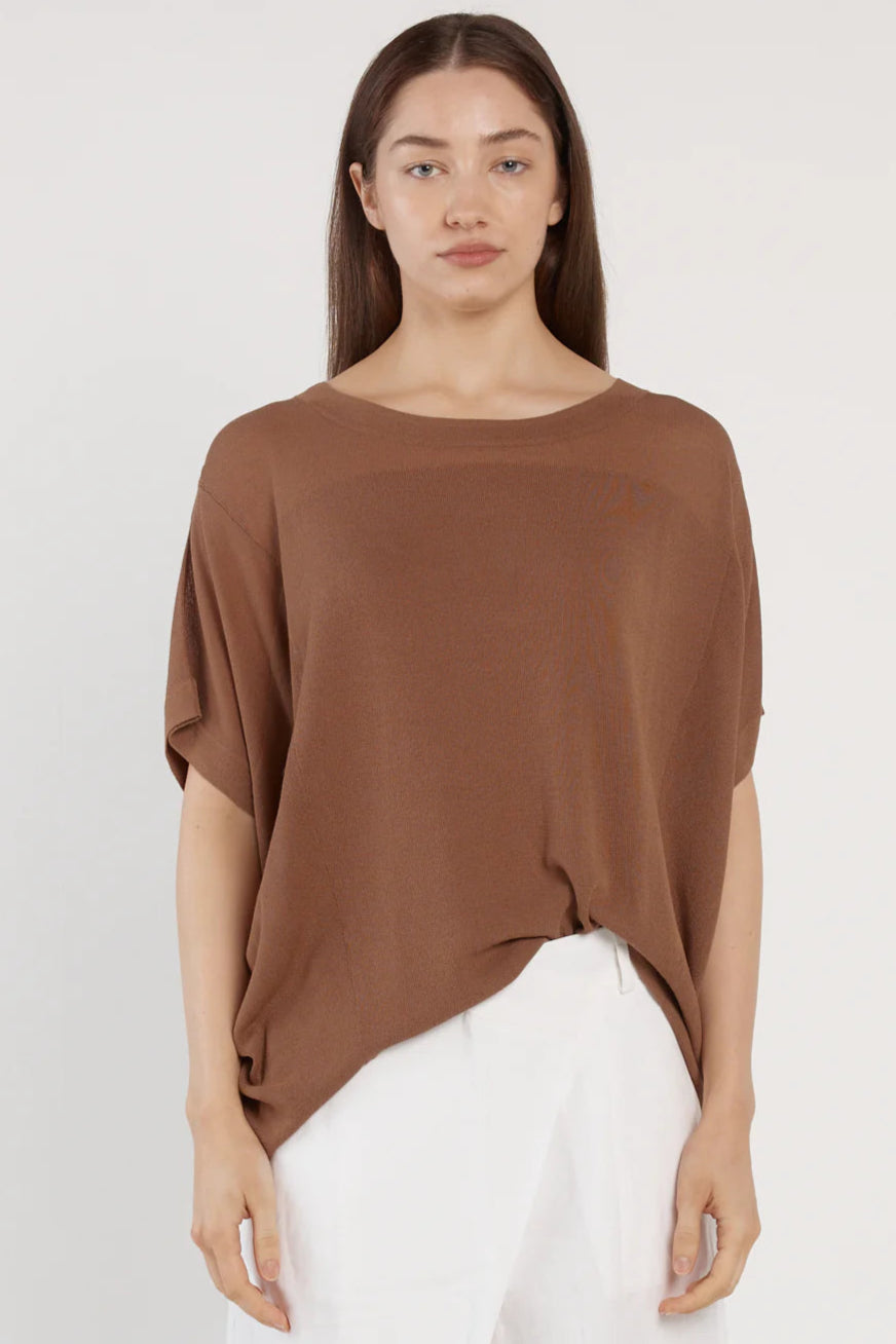 Woman wearing a brown fate & becker top and white pants against a white background