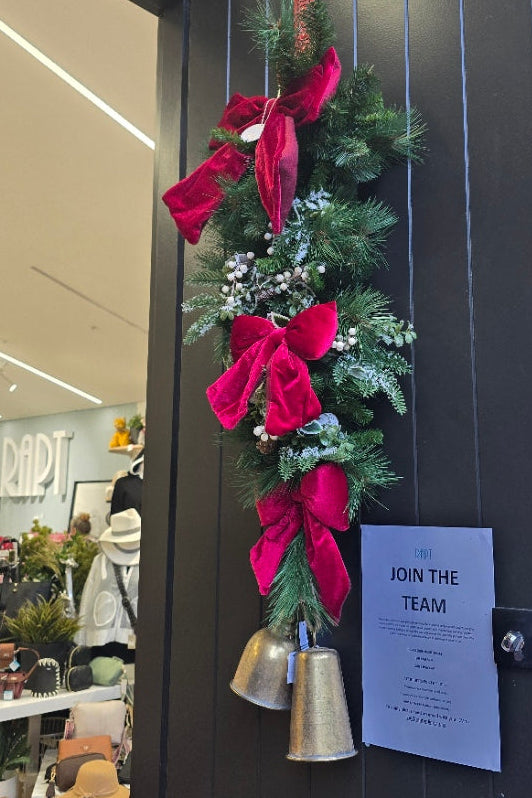 Decorative wreath with red ribbons and a bell on a door, with a menu attached.