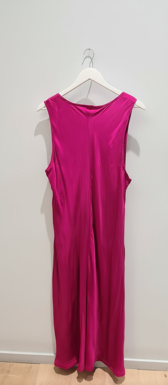 Fuchsia dress on a hanger against a plain wall