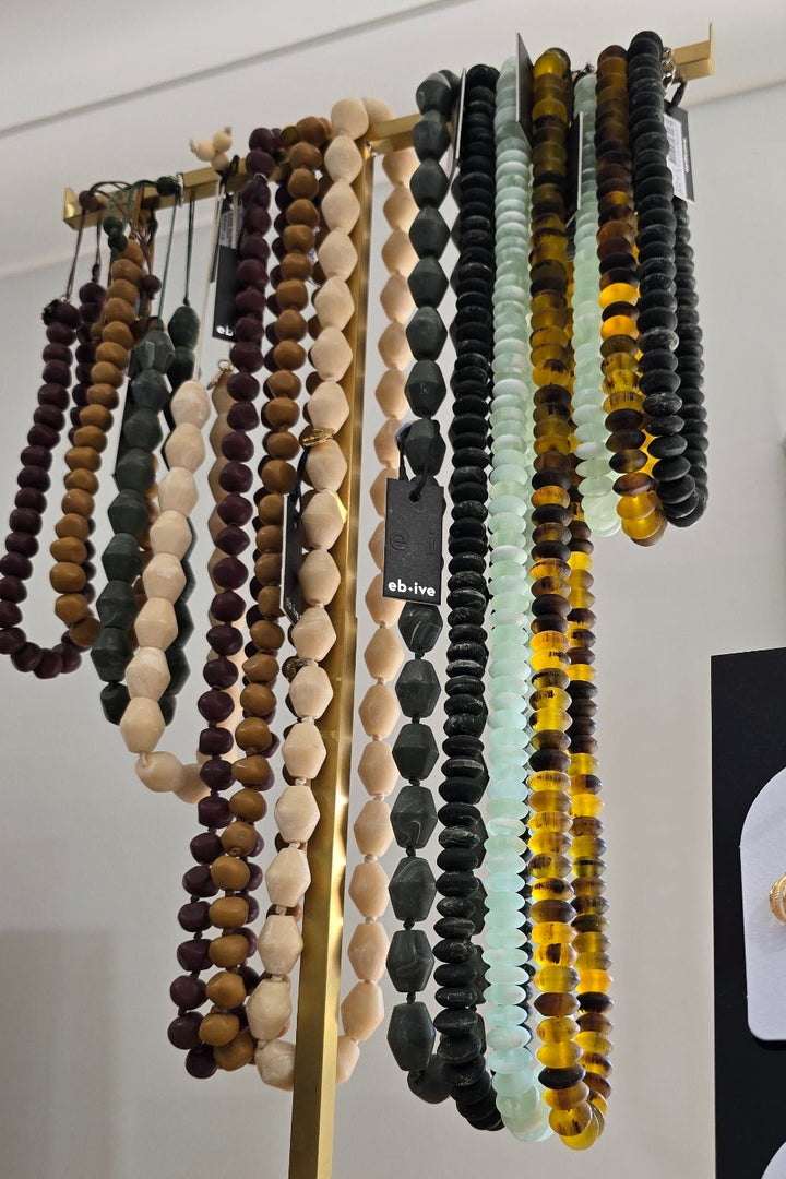 Collection of beaded bracelets on a stand with a mirror and additional jewelry in the background.