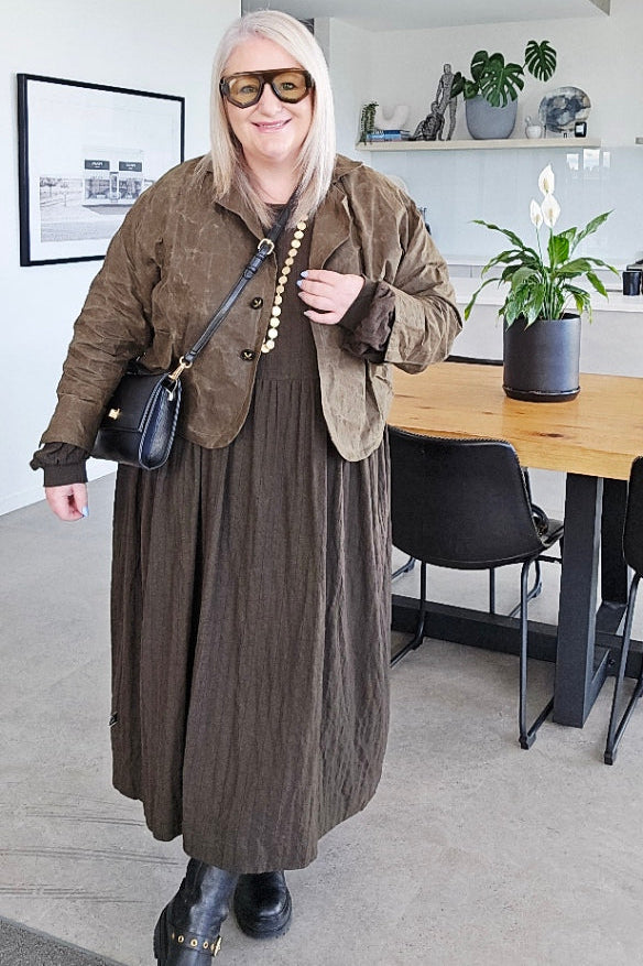 Person wearing a long brown coat in an indoor setting with modern decor.