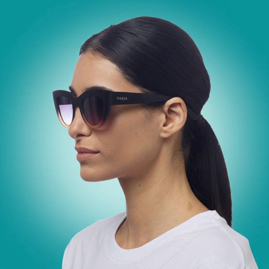 Woman wearing black sunglasses with 'OKKIA' branding on a white background