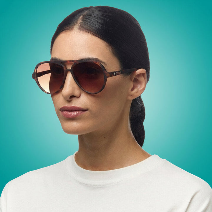 Woman wearing okkia sunglasses with a plain background