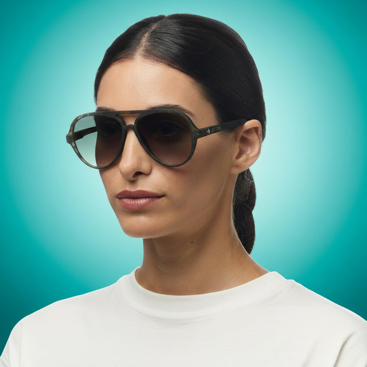 Woman wearing dark okkia sunglasses with a plain background