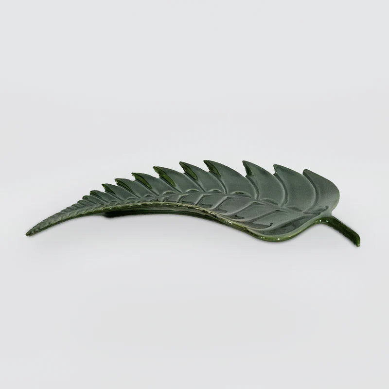 A dark green leaf-shaped ceramic plate with detailed embossed leaf veins, shown on a plain light gray background.
