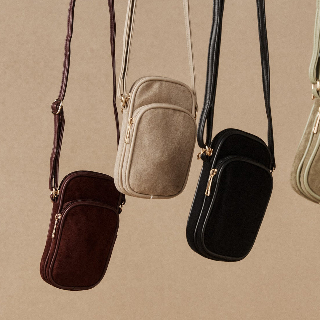 Five small bags hanging on a rod against a beige background