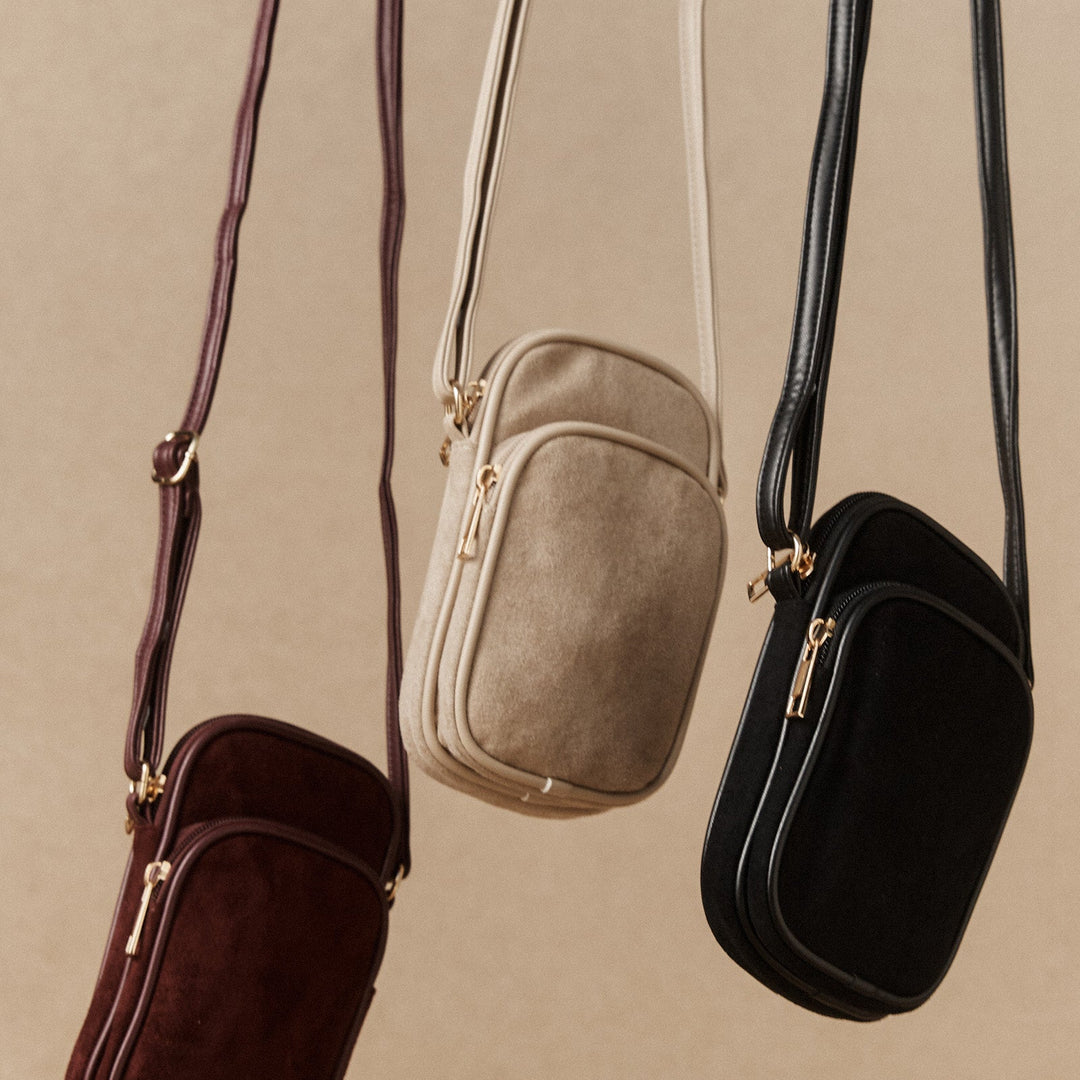 Three crossbody bags in brown, beige, and black on a beige background