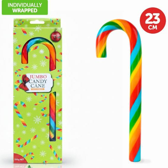 A jumbo rainbow-striped candy cane shown next to its green individually wrapped retail packaging. The candy cane has diagonal stripes of red, orange, yellow, green, blue, and purple.