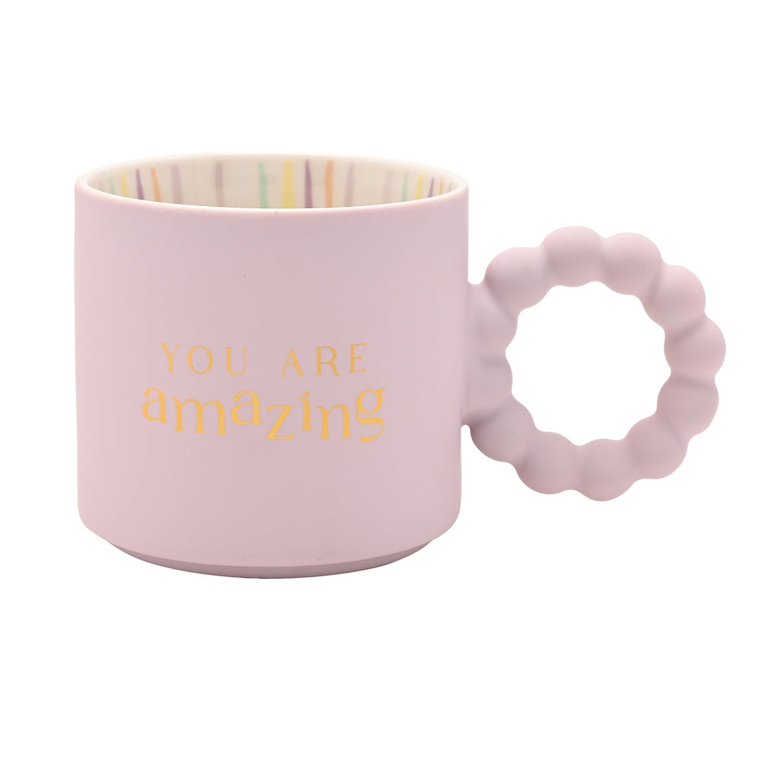 Pink mug with textured handle and 'YOU ARE amazing' text on a white background