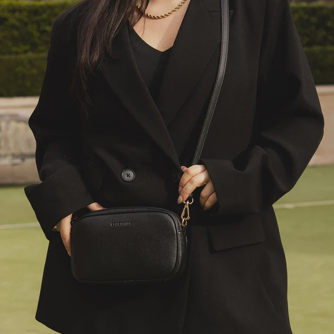 Person holding a black handbag outdoors